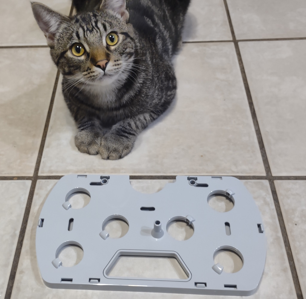 Toby the cat shows off the AeroGarden Harvest growing tray, upside down on the tile floor