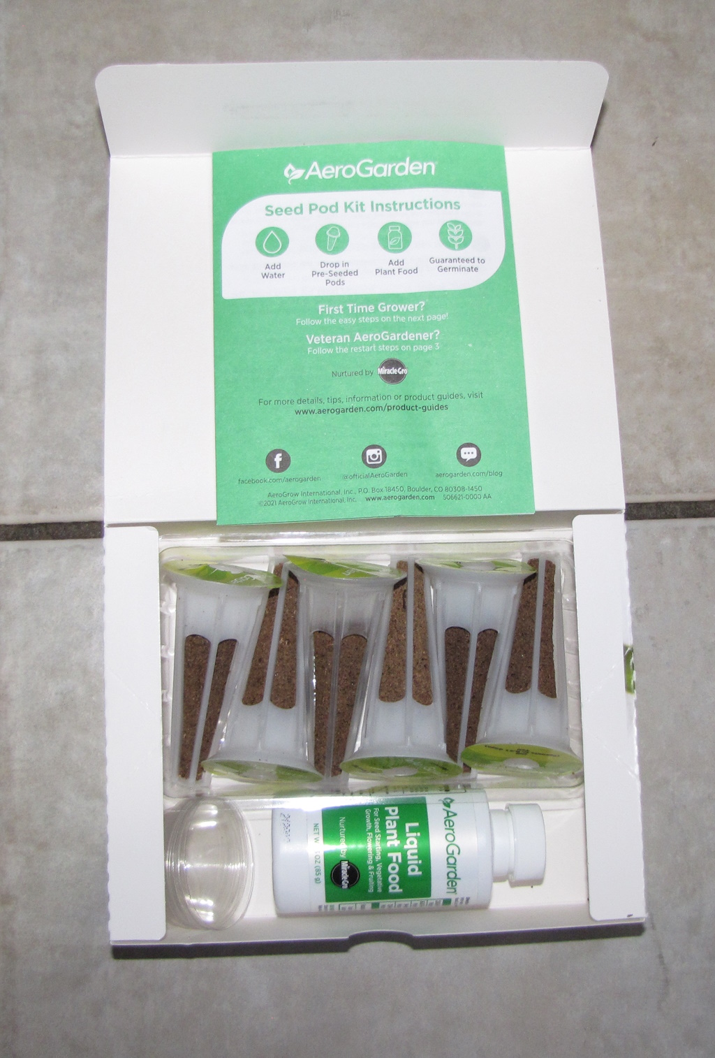 Initial view of the contents of the AeroGarden seed pod kit, with booklet set on box lid