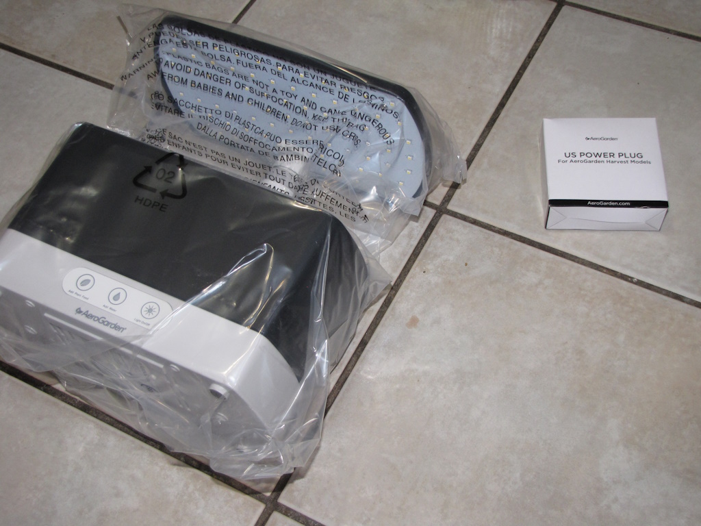 AeroGarden Harvest laid on its back next to the box containing the power plug